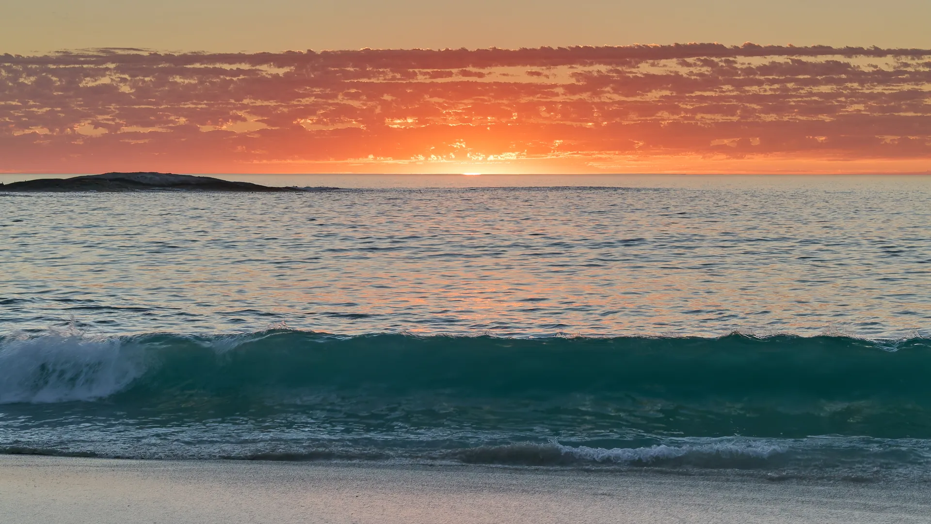 Vibrant sunset with turquoise wave breaking on a sandy beach, Camps Bay, Cape Town, South Africa